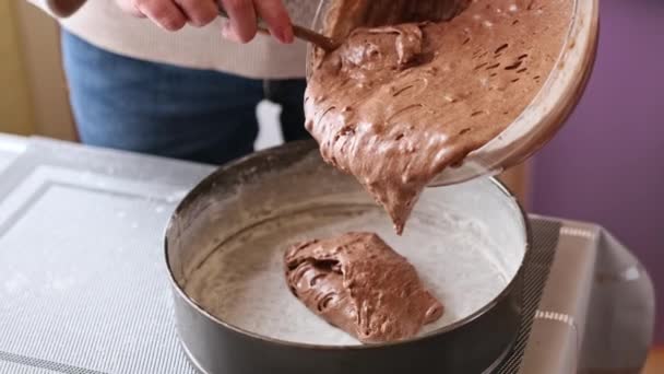 Woman puts chocolate dough with nuts dough in a baking dish — Stock video