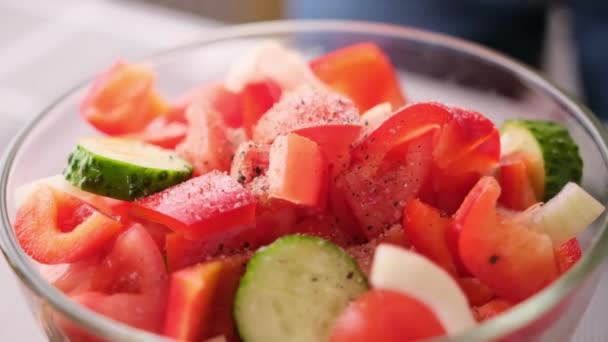 Greek salad preparation series concept - woman peppers chopped vegetables in a glass bowl — Stock video