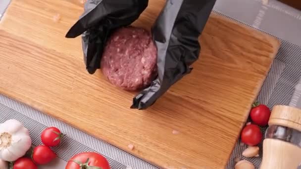 Köchin in schwarzen Handschuhen bereitet in der heimischen Küche Schnitzel auf einem Holzschneidebrett zu — Stockvideo