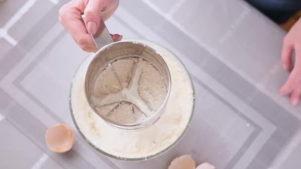 Woman sift flour through metallic sieve to glass bowl for baking — Videoclip de stoc