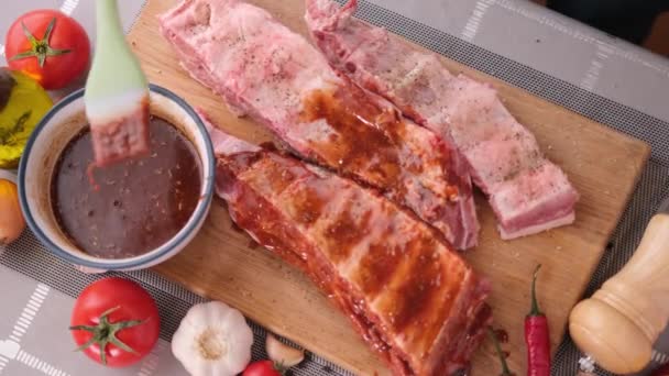 Ribs get glazed with brush with sweet barbeque sauce in slow motion closeup — ストック動画