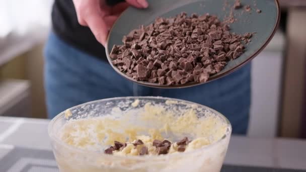Pouring chocolate into dough in glass bowl preparing homemade cookies at home — Vídeos de Stock