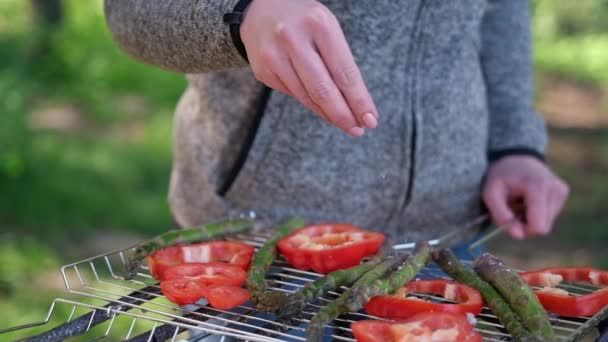 Robienie grillowanych warzyw - solone szparagi i czerwona papryka na grillu węglowym — Wideo stockowe