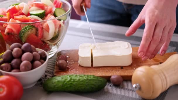 Greek salad preparation series concept - woman cutting feta cheese — стоковое видео