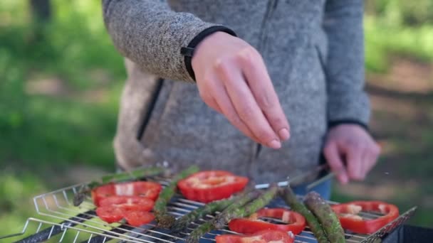 Robienie grillowanych warzyw - solone szparagi i czerwona papryka na grillu węglowym — Wideo stockowe