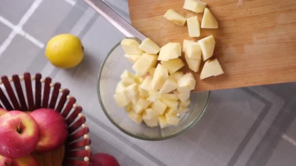 Apple pie preparation series - woman pours chopped apples into a glass bowl — Stok Video