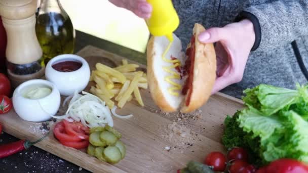 Making Hotdog - Woman Pouring mustard into bun — стоковое видео