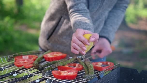Making grilled vegetables - adding lomon juice to Asparagus and red pepper on a charcoal grill — Stock video
