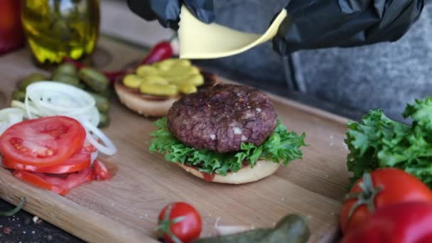 Making burger - Putting slice of cheddar cheese on a cutlet — Vídeo de Stock