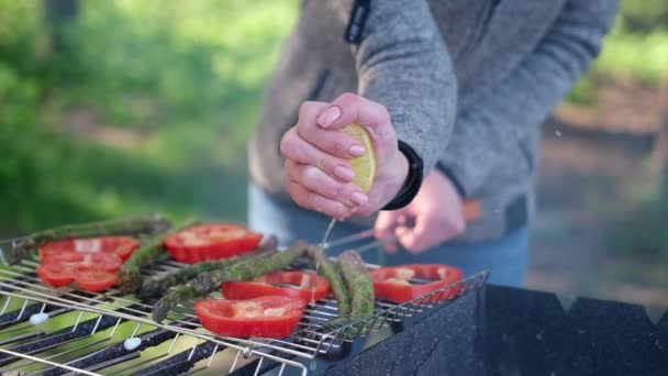 Making grilled vegetables - adding lomon juice to Asparagus and red pepper on a charcoal grill — 图库视频影像
