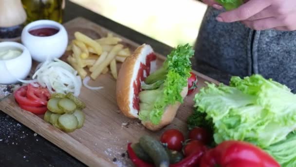 Making Hotdog - Woman adding salad to bun — стоковое видео