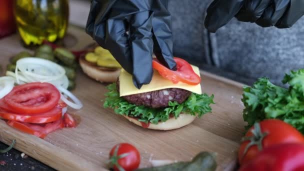 Hacer hamburguesa - Poner rebanadas de tomate en un queso cheddar — Vídeo de stock