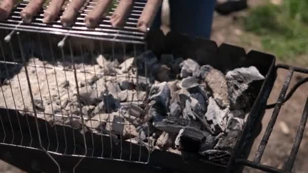 Kładąc kiełbaski na ruszcie grilla węglowego — Wideo stockowe