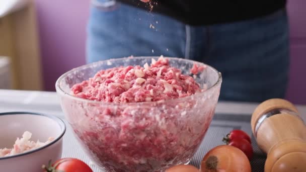 Přidávání soli a koření do mletého masa s cibulí a kořením ve skleněné misce na výrobu řízků — Stock video