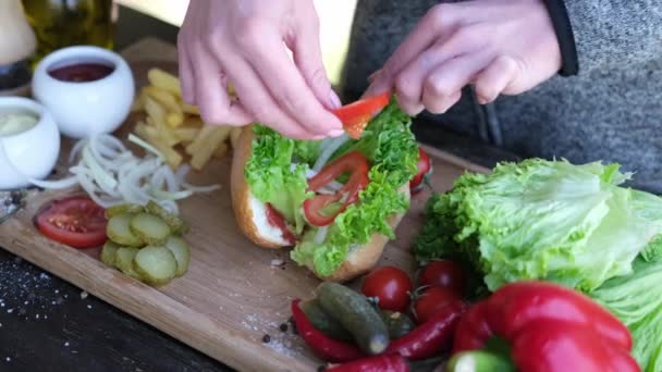 Hotdog maken - Vrouw die gesneden tomaten aan broodjes toevoegt — Stockvideo