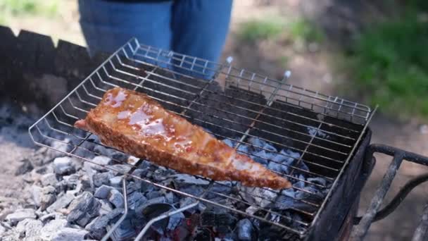 Colocando saboroso e delicioso churrasco costelas de porco grelhadas ao ar livre frito na grelha de carvão de madeira — Vídeo de Stock