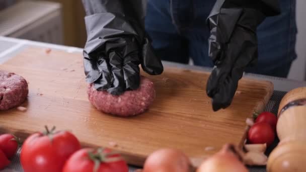 Köchin in schwarzen Handschuhen bereitet in der heimischen Küche Schnitzel auf einem Holzschneidebrett zu — Stockvideo