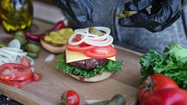Hacer hamburguesa - Poner encurtidos en rodajas en un ensamblaje de sándwich — Vídeos de Stock