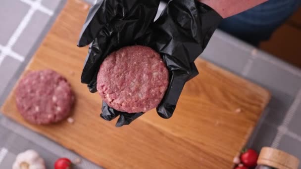 Жінка-кухарка в чорних рукавичках готує котлети на домашній кухні на дерев'яній обробній дошці — стокове відео