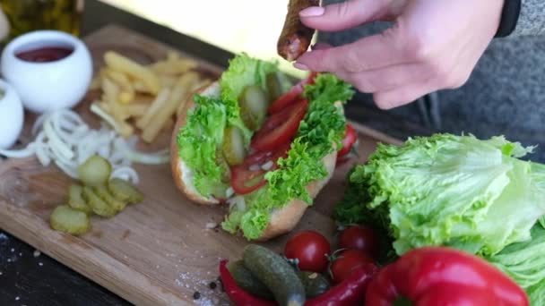 Хот-дог - женщина добавляет жареную колбасу в булочку — стоковое видео