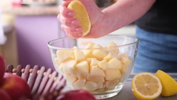 Appeltaart voorbereiding serie - vrouw persen citroensap in glazen kom met gehakte appels — Stockvideo