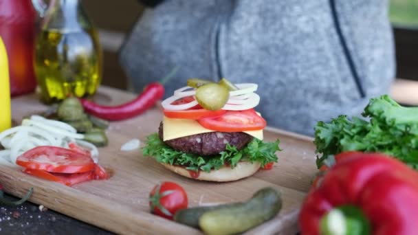 Göra hamburgare - Lägga andra halvan av en bulle efterbehandling smörgås montering — Stockvideo