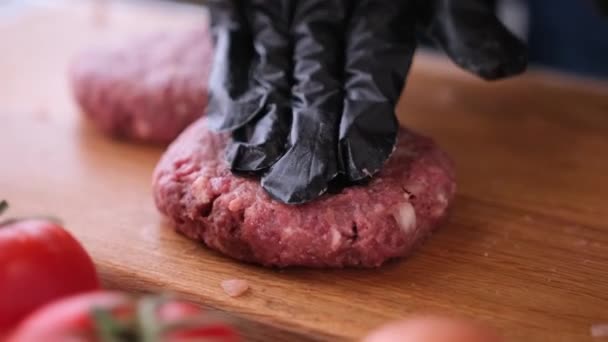 Siyah eldivenli kadın aşçı, ahşap bir kesme tahtasıyla ev mutfağında pirzola hazırlıyor. — Stok video