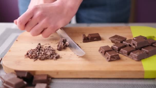 Frau hackt schwarze dunkle Schokolade auf Holzschneidebrett — Stockvideo