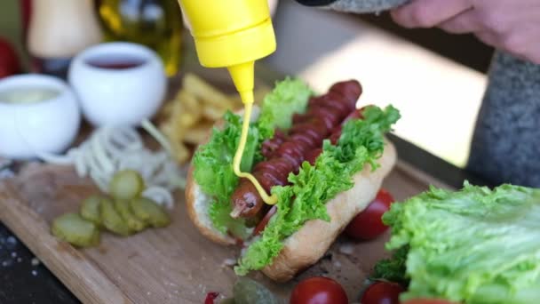 Hotdog maken - Vrouw die mosterdsaus op gegrilde worst giet — Stockvideo