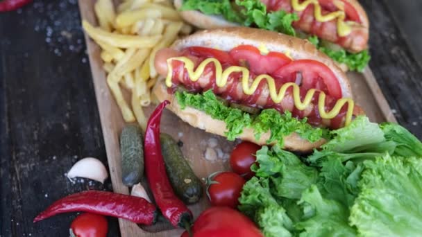 Čerstvě ugrilované hotdogy a hranolky na dřevěné desce — Stock video