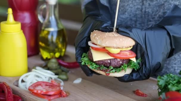 Gros plan d'une main féminine tenant un cheeseburger à l'extérieur — Video