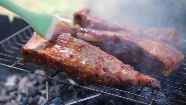 Heerlijke rundvlees of varkensribben bakken op een houtskoolgrill wordt bedekt met rode jus saus borstel — Stockvideo