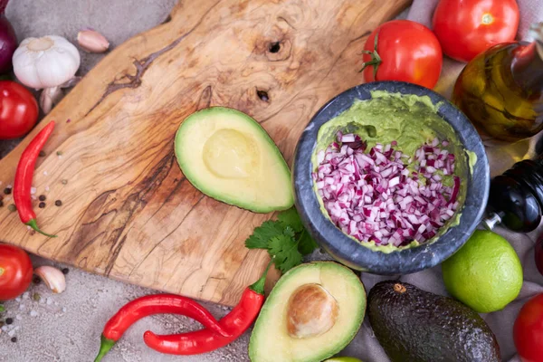 making guacamole - crushed avocado in marble mortar and ingredients.