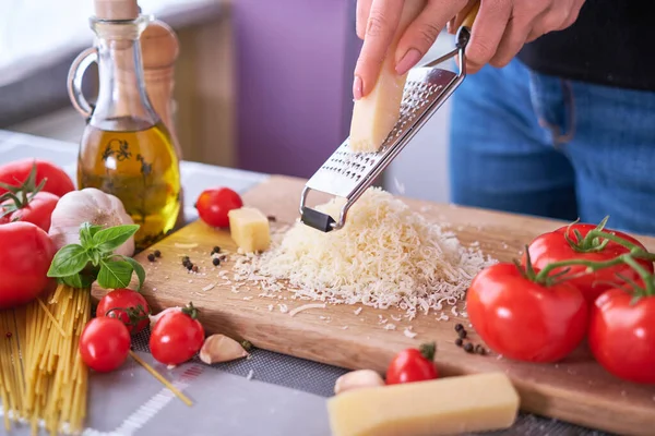 grating parmesan on a wooden gutting board at domestic kitchen.