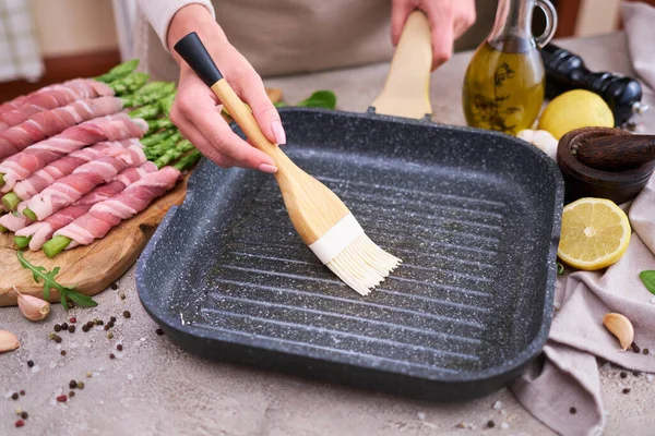 Woman Smearing Oil Grill Pan Cook Aspargus Covered Bacon — Stock Photo, Image