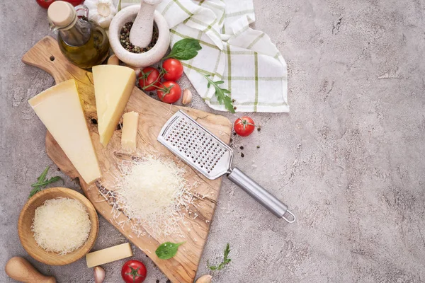 Parmesan cheese and grater on a wooden cutting board.