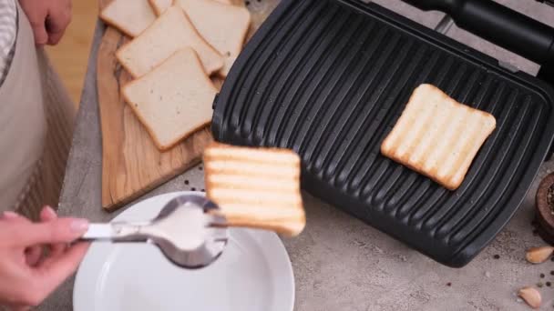 家庭用キッチンテーブルで白パンのトーストを作る女性 — ストック動画