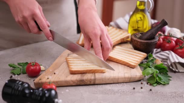 妇女在木制切菜板上切成两半烤面包片 — 图库视频影像