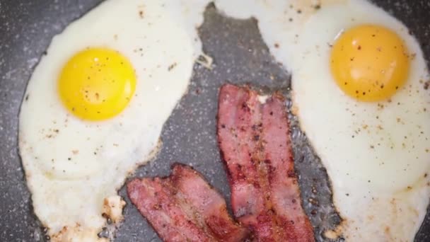 おいしい朝食を調理する フライパンにベーコンスライスと卵を揚げ — ストック動画