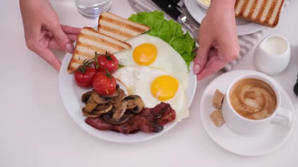 女人把装有美味早餐的盘子放在桌上 桌上有咖啡 奶油或牛奶 — 图库视频影像