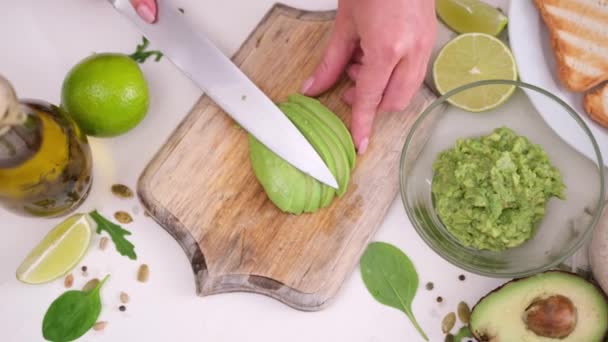 Frau Schneidet Geschälte Halbierte Avocado Auf Holzschneidebrett — Stockvideo