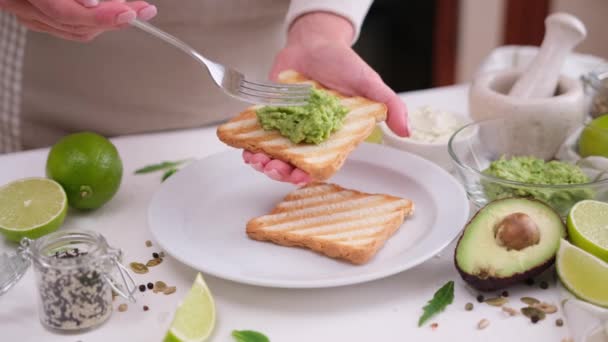 アボカドのサンドイッチを調理する 女性はトーストパンにマッシュポテトを微笑む — ストック動画