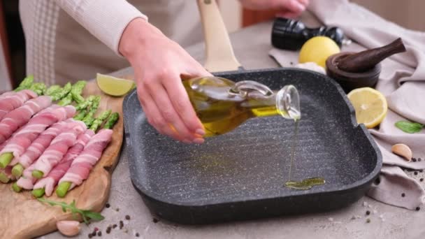 女人们在烤油锅里倒橄榄油 同时用熏肉包芦笋 — 图库视频影像
