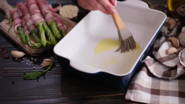 Γυναίκα Αλείφει Ελαιόλαδο Ταψί Πινέλο Σιλικόνης Ενώ Μαγειρεύει Σπαράγγια Τυλιγμένα — Αρχείο Βίντεο