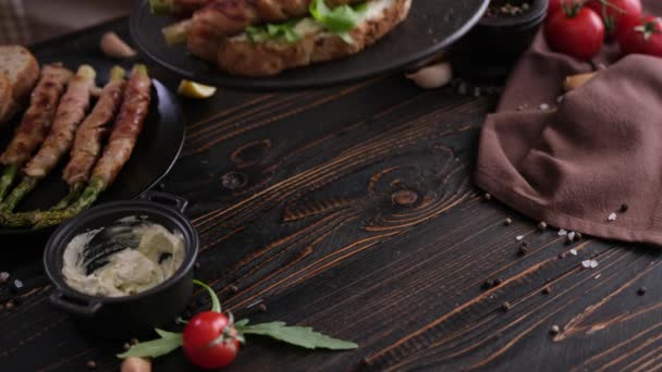 在家里的厨房里 用熏肉和奶油芝士三明治包裹在黑色陶瓷盘上的芦笋 — 图库视频影像