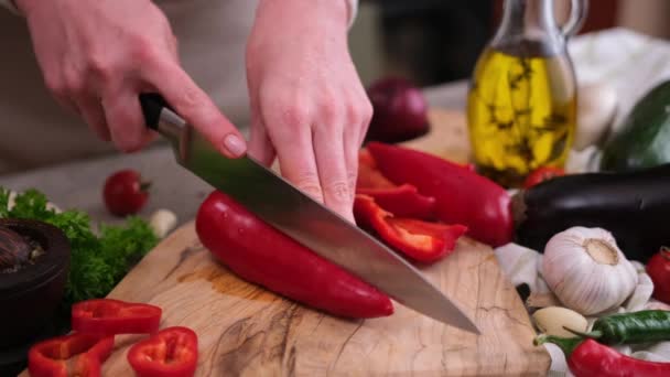 女性は木の板にナイフで新鮮な赤唐辛子をスライス切断 — ストック動画