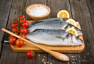 Raw sea bass on a wooden board clipart