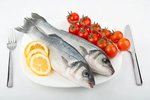 Dois peixes robalo com limão e tomate — Fotografia de Stock