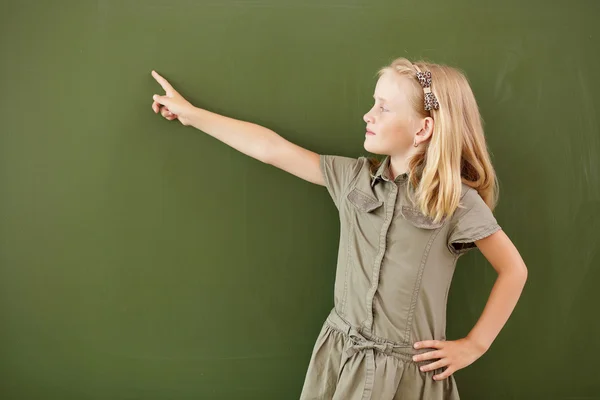 Scoolgirl staande in de buurt van blackboard — Stockfoto