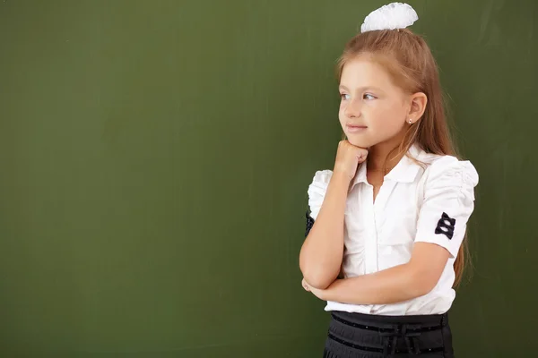 Scoolgirl står nära blackboard — Stockfoto